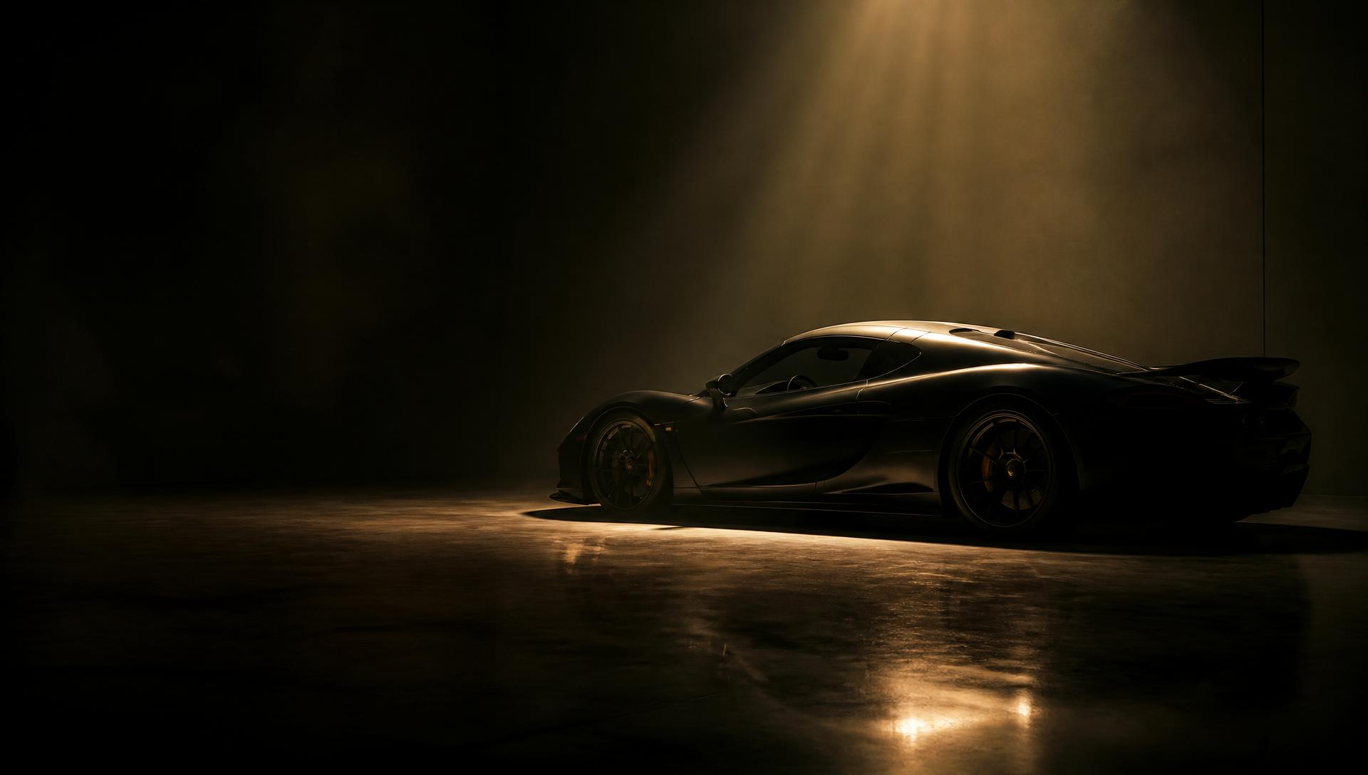 An exotic motor car in a darkened private showroom lit by a single warm spotlight